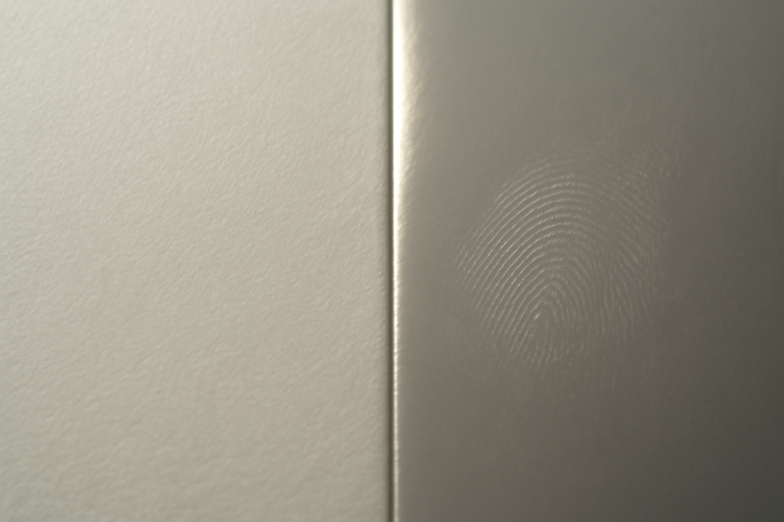 Extreme macro of two photo paper surfaces meeting at a seam — matte on the left with an even velvety tooth, glossy on the right with a bright specular highlight and a visible fingerprint